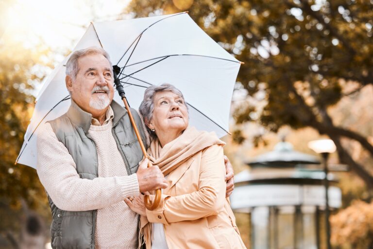 senior-couple-umbrella-and-walking-outdoor-for-relax-freedom-calm-quality-time-and-relationship-b-768x512